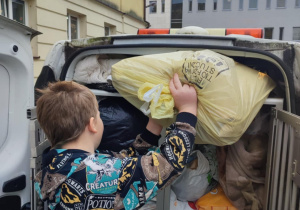 Chłopiec pakuje poduszki do schroniska