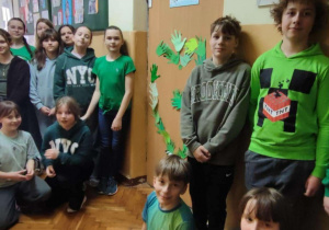 Uczniowie ubrani na zielono stoją w korytarzu szkolnym