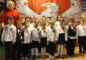 Dzieci z oddziału przedszkolnego przy ściance z białym orlem na czerwonym tle