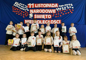 Nagrodzeni uczniowie na wspólnym zdjęciu przy dekoracji okolicznościowej