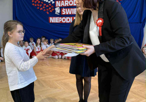Pani dyrektor wręcza nagrodę uczennicy klasy pierwszej