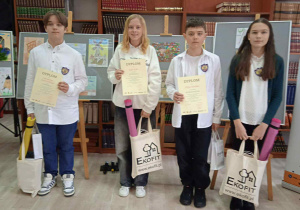 Nagrodzeni uczniowie reprezentujący szkołę na wspólnym zdjęciu z nagrodami i dyplomami