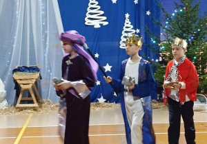 Uczniowie przebrani za Trzech Króli podążają do stajenki