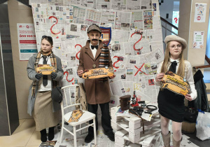 Uczniowie przebrani za detektywów pozują do zdjęcia na ściance