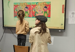 Dziewczynka rozwiązuje zagadkę na tablicy multimedialnej