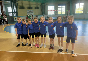 Chłopcy i dziewczynki z klas drugich w strojach sportowych pozują do zdjęcia przed startem w zawodach