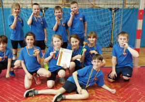 Drugoklasiści pozują do zdjęcia z pucharem, dyplomem i medalami