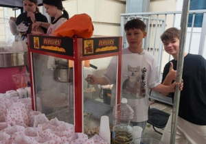 Uczniowie stoją przy maszynie z popcornem