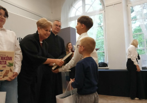Uczeń odbiera gratulacje z rąk pani dyrektor Wydziału Edukacji