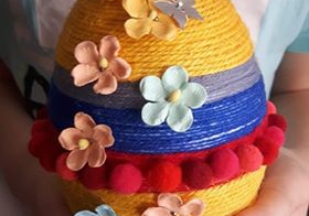 Jajo styropianowe ozdobione kolorowymi sznurkami i kwiatami