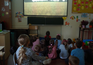 Dzieci oglądają film edukacyjny na temat powstawania pracy rolników, produkcji maki i chleba