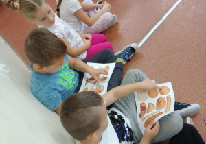 Dzieci oglądają ilustracje przedstawiające różne rodzaje pieczywa