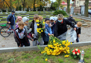 Dzieci otrzymują kwiaty na groby żołnierzy