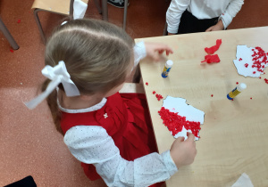 Dzieci wyklejają kontury mapy Polski bibułą.