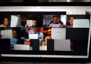 Uczniowie na ekranie komputera z karteczkami przedstwiającymi uśmiech