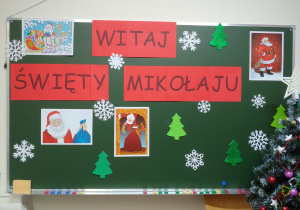 Napis "Witaj Święty Mikołaju" oraz ilustracje przedstawiające Mikołaja przytwierdzone do tablicy