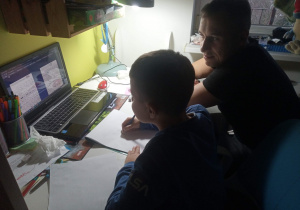 Chłopiec z klasy 2b pracuje z tatą przy komputerze pisząc list do Mikołaja