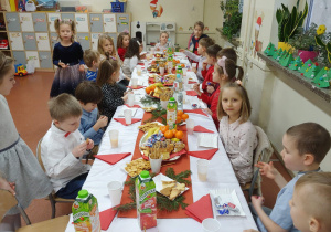 Dzieci siedzą przy odświętnie udekorowanym stole