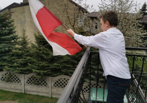 Chłopiec wiesza flagę Polski