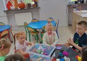 Dzieci siedzą przy stoliku i bawią się plasteliną