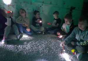 Odbicie światła- dzieci eksperymentują, próbują odbić światło latarki za pomocą lusterka