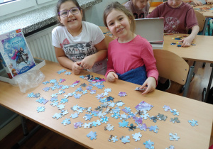Dziewczynki uśmiechają się podczas układania puzzli.