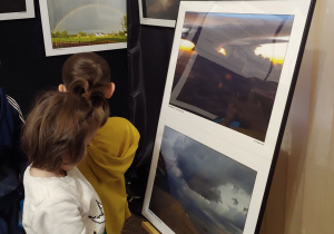 Uczeń ogląda fotografie prezentujące chmury