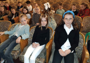Trzy dziewczynki siedzą w fotelach w teatrze czekając na przedstawienie