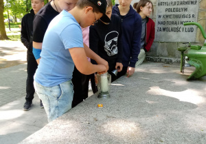 Uczniowie klasy 7b pod pomnikiem 14 Brygady zapalają znicz