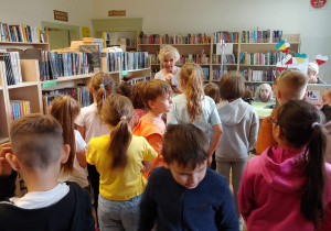 Uczennica zgromadzeni w bibliotece między regałami z książkami