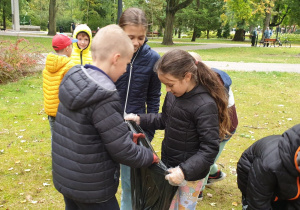 Uczniowie zbierają śmieci w parku