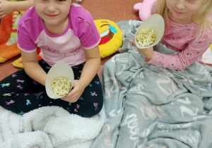 Dziewczynki oglądają bajkę i jedzą popcorn