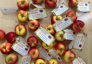 Jabłka z etykietkami na których wypisane jest dlaczego warto jeść jabłka