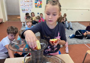 Dziewczynka wkłada jabłka do sokowirówki