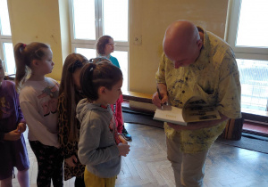 Łukasz Wierzbicki składa autograf w książce ucznia klasy 2a.