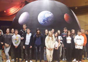 Uczniowie stoją w sali gimnastycznej przed mobilnym planetarium