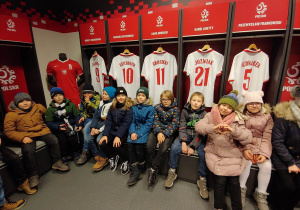 Uczniowie klasy 2a uśmiechają się do zdjęcia podczas pobytu w szatni polskich piłkarzy.