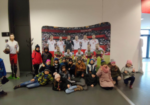 Chłopcy i dziewczynki ustawieni przed zdjęciem reprezentacji Polski w piłce nożnej.