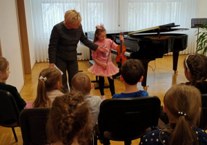 Dziewczynka prezentuje przed widownią skrzypce