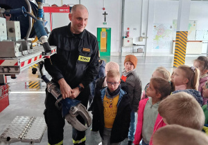 Strażak prezentuje dzieciom sprzęt strażacki