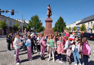 Dziewczynki i chłopcy stoją przed pomnikiem Tadeusza Kościuszki