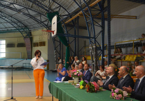 Pani dyrektor Aneta Jarząbek w hali sportowej przemawia do zaproszonych gości