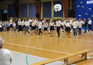 Trzecioklasiści tańczą na środku hali