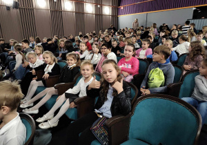Dziewczynki i chłopcy pozują do zdjęcia w sali teatralnej