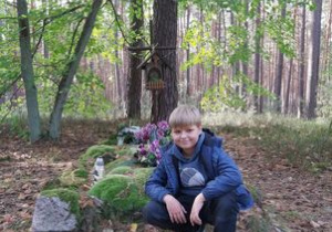 Uczeń przy mogiłach w lesie koło Dąbrowy