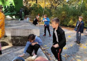 Dzieci sprzątają miejsce wokół pomnika
