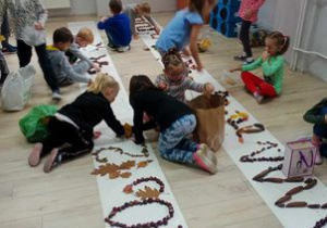 Dzieci układają różne wzory z kasztanów, żołędzi i szyszek
