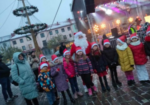 Dzieci przed wejściem na scenę na wspólnym zdjęciu z Mikołajem