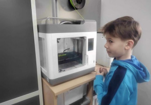Uczeń stoi przy drukarce modeli 3D