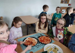 Dzieci jedzą samodzielnie przygotowaną pizzę